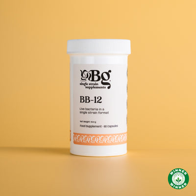A white plastic bottle of BB-12 Single Strain BetterGuts Supplements BB-12 live bacteria, set against a solid light yellow background with a small green Vegan choice awards winners badge in the bottom right corner.